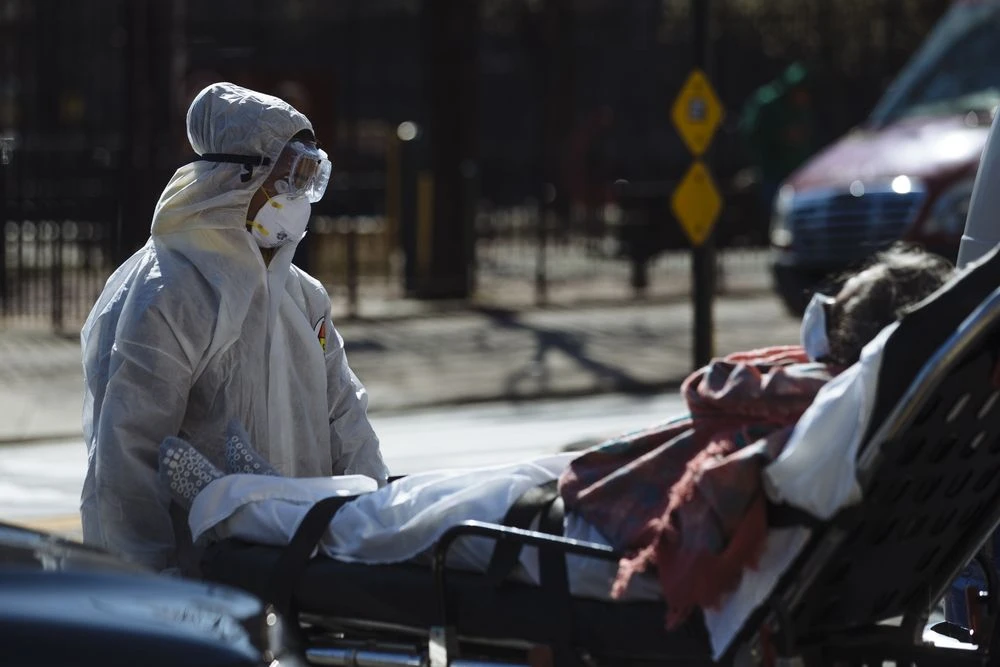 A medical worker pushes a stretcher outside the Elmhurst Hospital Center in the Queens borough of New York, on March 26. Photographer: Angus Mordant/Bloomberg