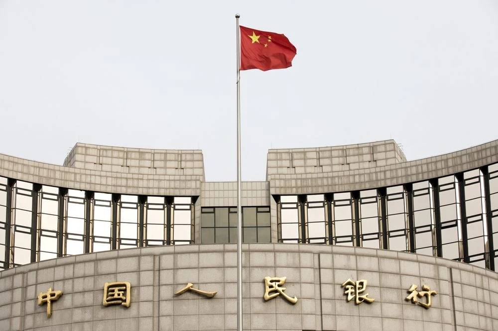 A Chinese flag flies in front of the People's Bank of China headquarters in Beijing, China, on Monday, Jan. 7, 2019. The central bank on Friday announced another cut to the amount of cash lenders must hold as reserves in a move to release a net 800 billio