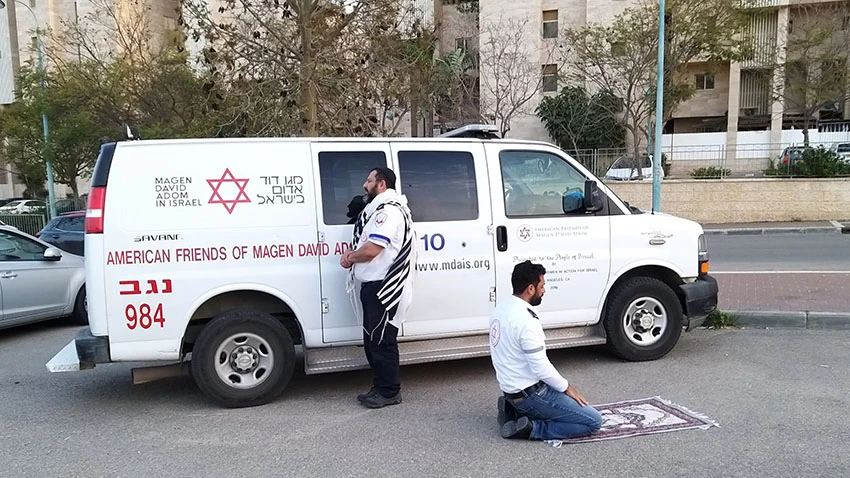 Các nhân viên y tế Do Thái và Hồi giáo thuộc dịch vụ khẩn cấp Magen David Adom của Israel cầu nguyện cùng nhau trong đợt bùng phát coronavirus. © Reuters