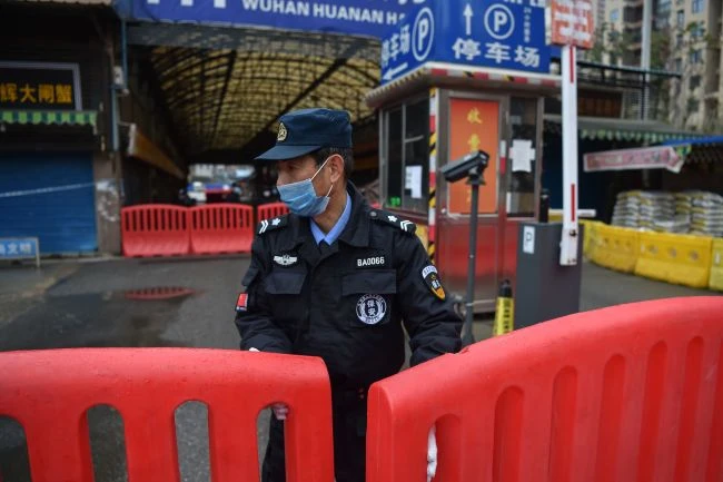 Trong một hình ảnh vào ngày 24 tháng 1, một sĩ quan cảnh sát đứng canh gác bên ngoài chợ bán buôn hải sản Huanan, nơi một số báo cáo cho rằng đại dịch bắt đầu. (Ảnh: © HECTOR RETAMAL / AFP qua Getty Images)