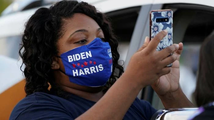 Một người ủng hộ Biden đang đọc tin nhắn văn bản. © Kevin Lamarque/Reuters