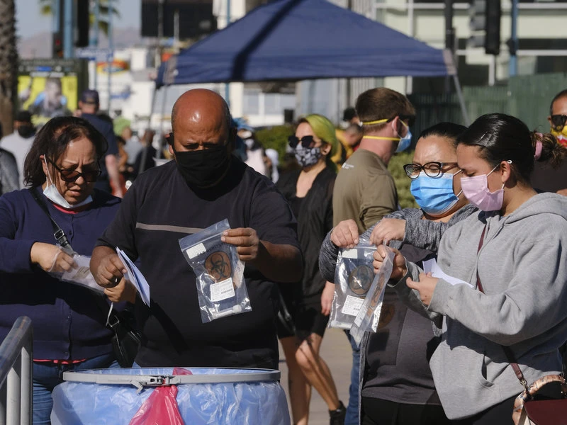 Mọi người thả bộ xét nghiệm của họ vào một thùng chứa tại một địa điểm thử nghiệm coronavirus ở khu vực Bắc Hollywood của Los Angeles vào thứ Bảy 5/12/2020. Ảnh: Richard Vogel/AP