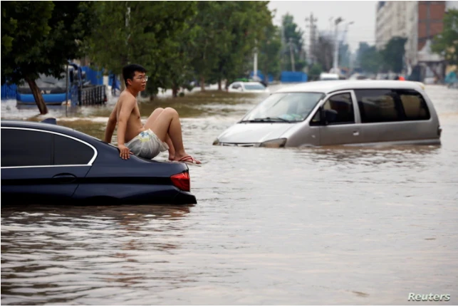 Một người đàn ông ngồi trên một chiếc xe bị mắc kẹt trên con đường ngập nước sau trận mưa lớn ở Trịnh Châu, tỉnh Hà Nam, Trung Quốc, ngày 22 tháng 7 năm 2021.