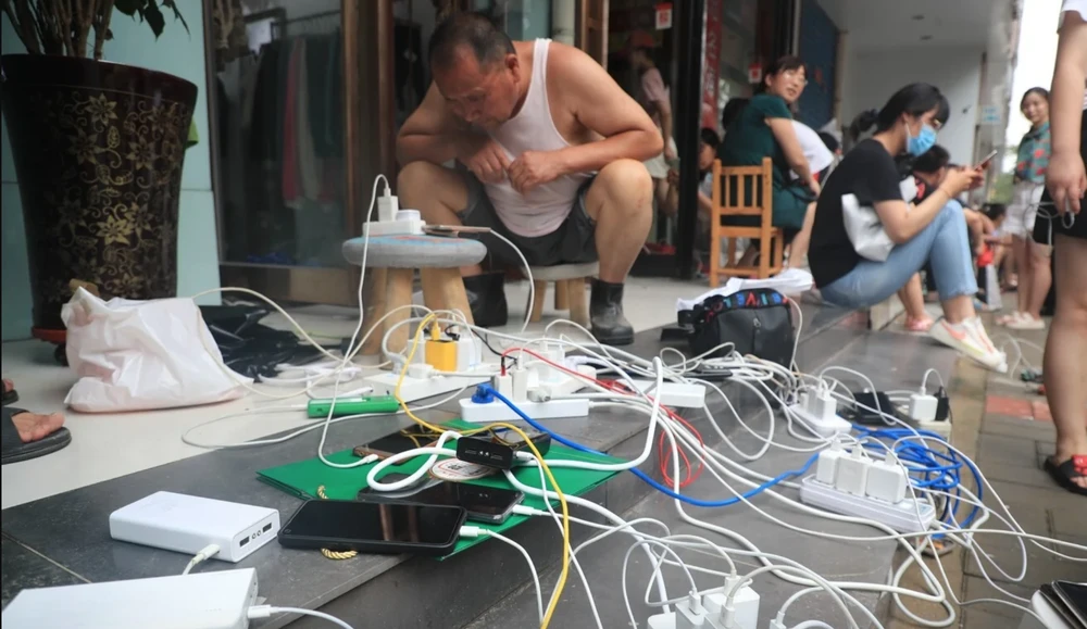  Mọi người sạc điện thoại di động bên ngoài một cửa hàng ở Trịnh Châu có điện. Ảnh: Getty Images