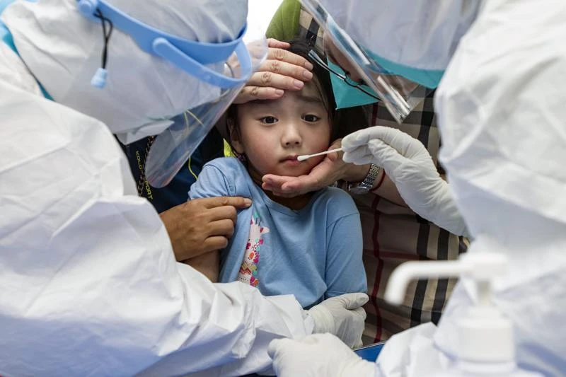 Một đứa trẻ phản ứng với miếng gạc ngoáy họng trong quy trình xét nghiệm hàng loạt tại Vũ Hán, Trung Quốc. Nguồn ảnh: APNews.