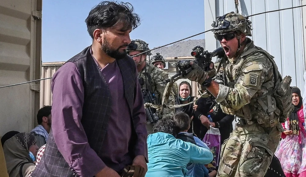  Một binh sĩ Mỹ chĩa súng về phía một người Afghanistan tại sân bay Kabul trong lúc hỗn loạn hôm 16-8. Ảnh: AFP