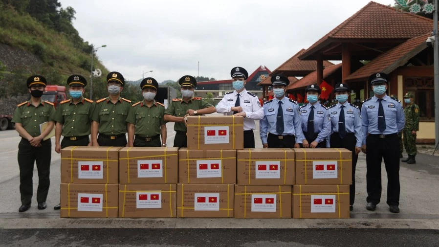Representatives of China and Vietnam pose for a group photo with COVID-19 prevention and control materials at a border crossing between China and Vietnam, on May 12, 2020. /Chinese Embassy in Vietnam
