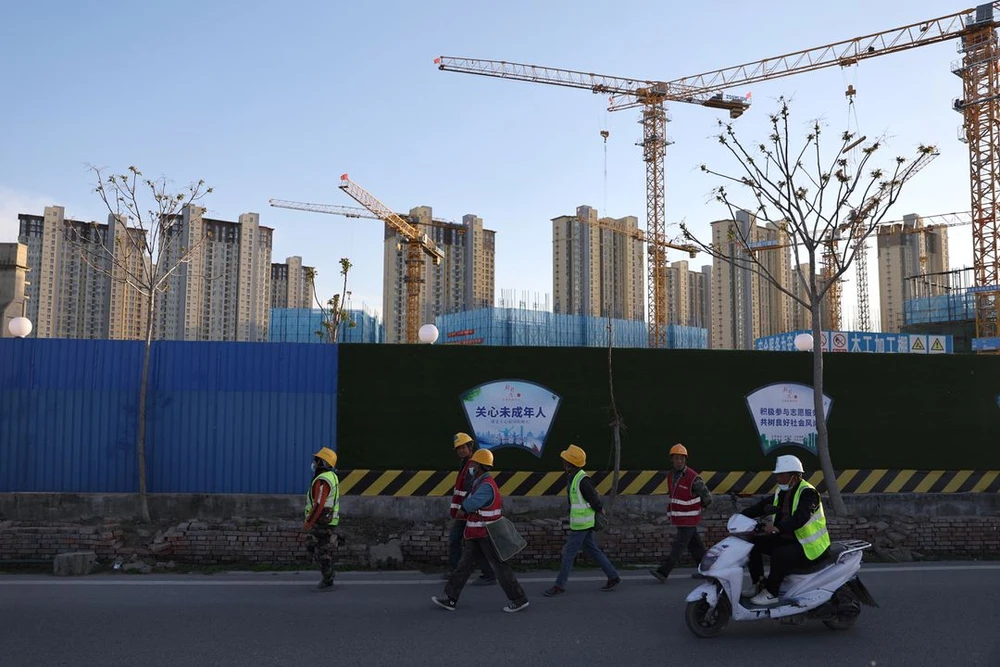 Công nhân đi ngang qua một công trường gần các tòa nhà dân cư ở Bắc Kinh, Trung Quốc ngày 14/4/2022. REUTERS/Tingshu Wang