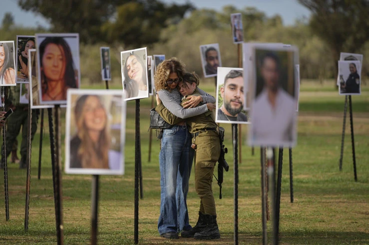 Người Israel ôm nhau cạnh những bức ảnh những người bị phiến quân Hamas giết hại và bắt giữ trong cuộc tấn công vào lễ hội âm nhạc Nova ở miền nam Israel hôm 7/10/2023.