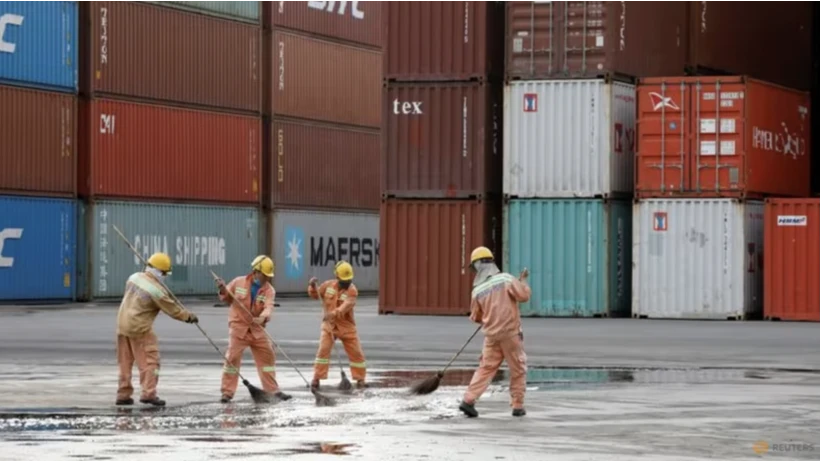 Workers clean the ground in front of containers at Tien Sa port in Da Nang city, Vietnam, March 6, 2020. REUTERS/Kham/File Photo