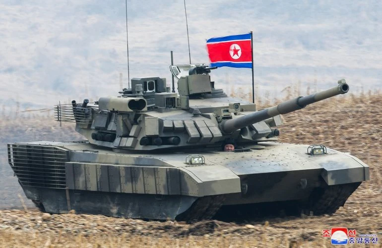 Ông Kim ngồi bên trong xe tăng trong cuộc trình diễn quân sự [KCNA via Reuters]