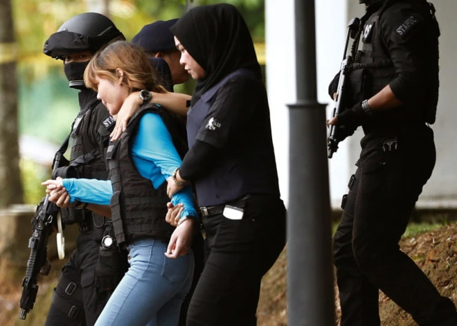 Đoàn Thị Hương (áo xanh) mặc áo chống đạn và được áp tải khỏi tòa hôm 13-4. Ảnh: Reuters.
