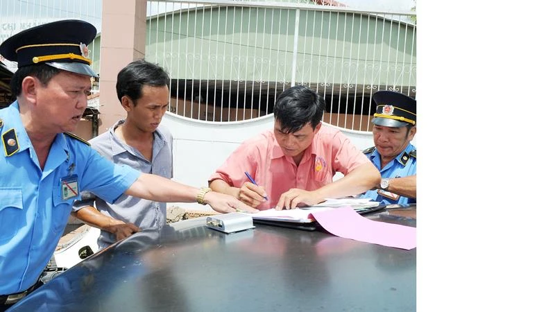Tài xế ký biên bản vi phạm luật giao thông tại cửa ngõ phía Đông thành phố Ảnh: CAO THĂNG