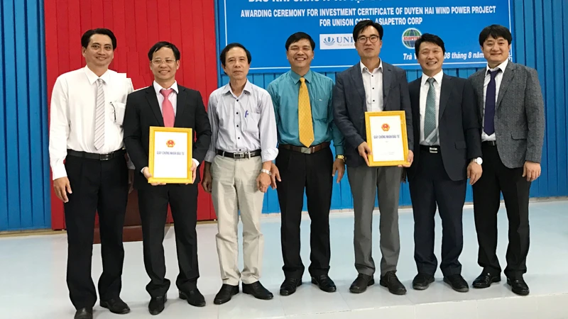 Ông Phạm Văn Tám (áo xanh), Trưởng Ban Quản lý Khu kinh tế tỉnh Trà Vinh trao giấy chứng nhận cho nhà đầu tư Dự án Nhà máy điện gió Duyên Hải