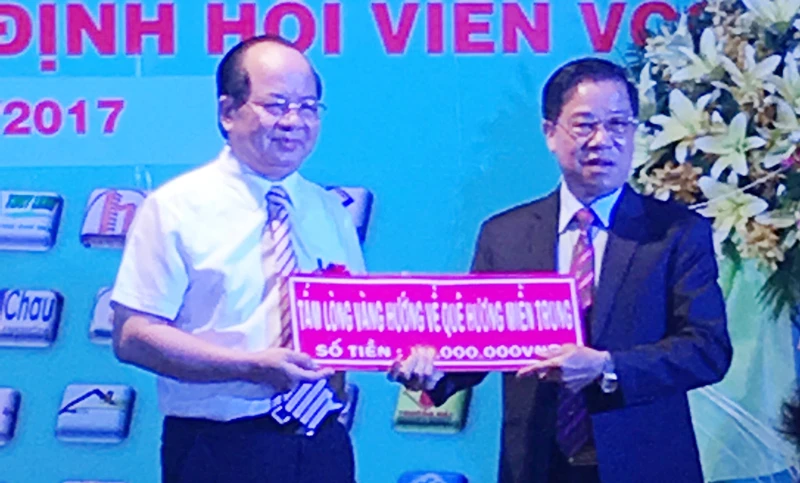 Viện sĩ, GS-TS Hoàng Quang Thuận (áo trắng) trao 100 triệu đồng cho Chủ tịch Câu lạc bộ ủng hộ đồng bào bị thiệt hại do cơn bão số 10 gây ra.