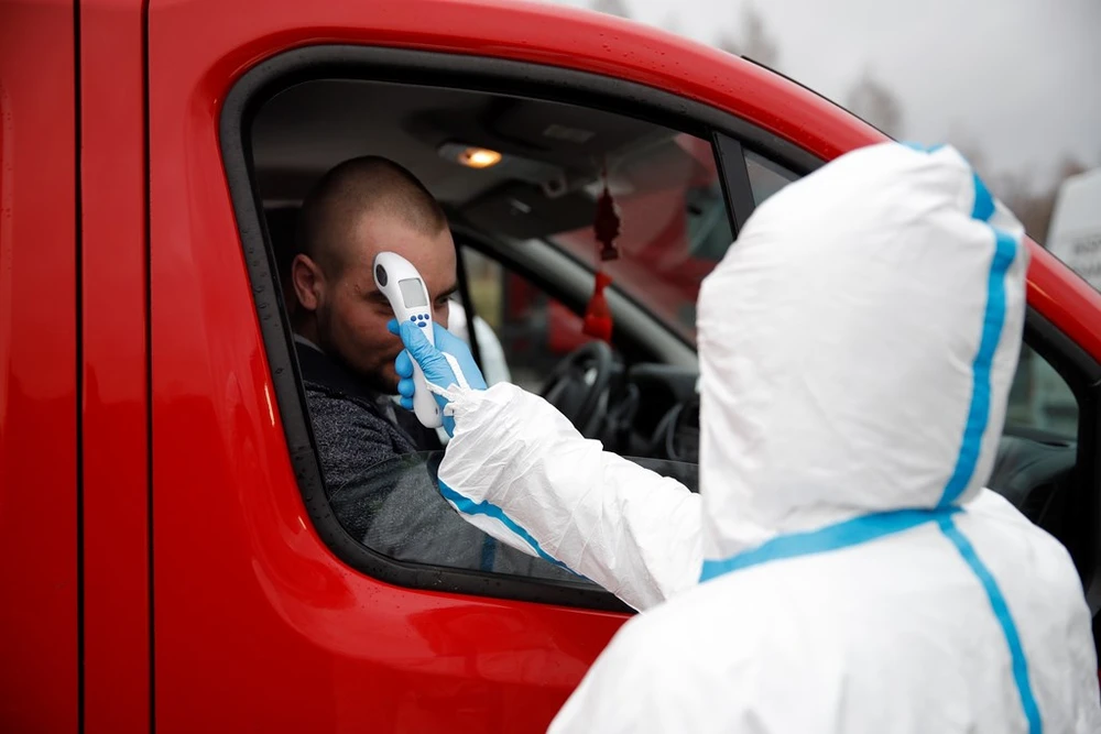 Nhân viên y tế kiểm tra thân nhiệt một lái xe tại khu vực cửa khẩu Jedrzychowice giữa Đức và Ba Lan, ngày 9-3-2020. Ảnh: AFP/TTXVN