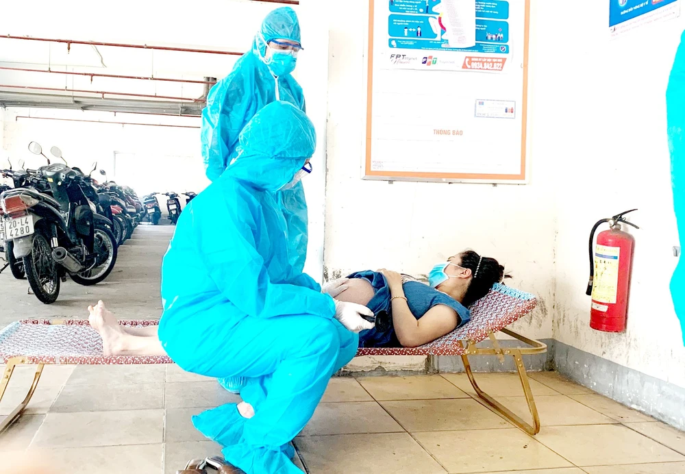 2 bác sĩ khám thai một cư dân trong khu vực phong tỏa. Ảnh: KHÁNH HƯNG
