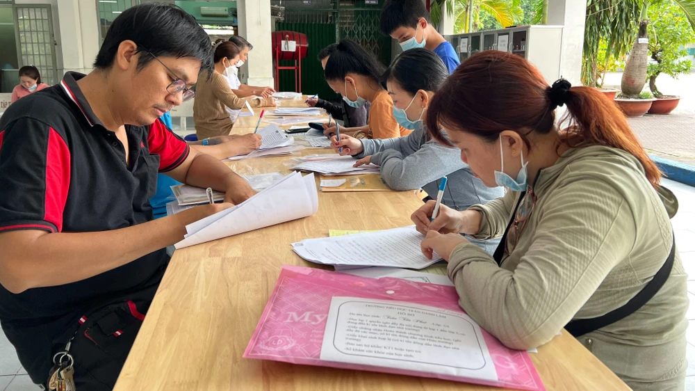 Phụ huynh làm thủ tục cho con nhập học lớp 6 Trường THCS Chánh Hưng, quận 8, TPHCM. Ảnh: CAO THĂNG 
