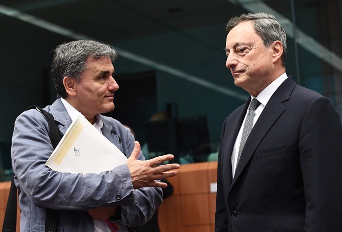 Greece’s Finance Minister Euclid Tsakalotos (left) speaks with European Central Bank President Mario Draghi during a Eurogroup finance ministers meeting on Monday at the European Council in Brussels. - AFP/VNA 