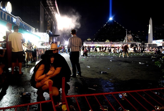 People take cover at the Route 91 Harvest country music festival after apparent gun fire was heard on October 1 in Las Vegas, Nevada.  AFP/VNS Photo