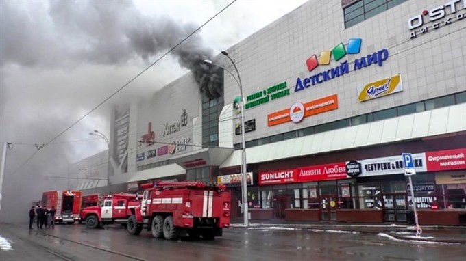 This handout picture released by the Russian Emergency Situations Ministry shows emergency vehicles as they gather outside a burning shopping centre in Kemerovo, in western Siberia. — AFP/VNA Photo
