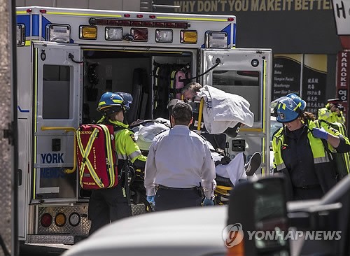 This photo released by the Associated Press shows rescue workers transporting an injured person into an ambulance in Toronto after a van mounted a sidewalk and crashed into pedestrians on April 23, 2018. (Yonhap)