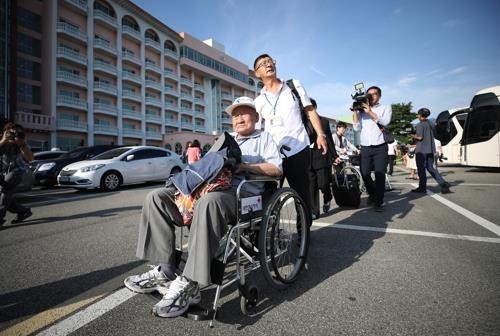 This photo taken by Joint Press Corps shows an elderly South Korean man in a wheelchair supported by his family moving to board a bus bound for a Mount Kumgang resort on North Korea's east coast, the venue for his long-awaited family reunion event. (Yonha