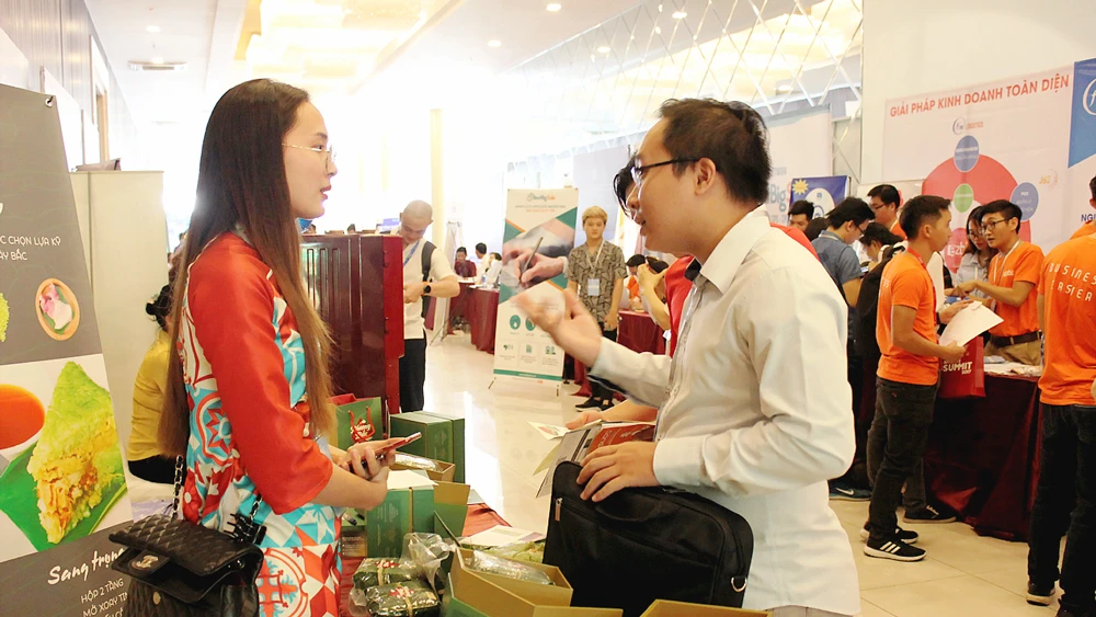 Một bạn trẻ (trái) giới thiệu thương hiệu sản phẩm bánh chưng đến khách hàng tại sự kiện về thương mại điện tử ngày 13-12 ở TPHCM