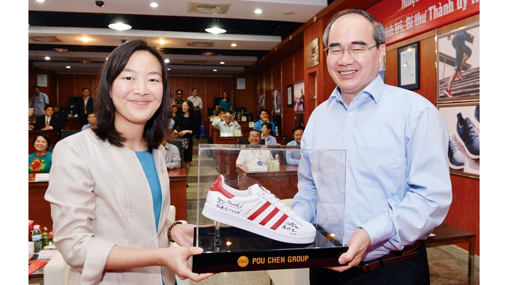 Bí thư Thành ủy TPHCM Nguyễn Thiện Nhân ký tặng lên sản phẩm giày của Công ty Pou Yuen Việt Nam. Ảnh: VIỆT DŨNG