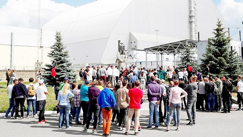 Du khách đứng bên ngoài mái vòm kim loại bảo vệ lò phản ứng thứ tư của Chernobyl