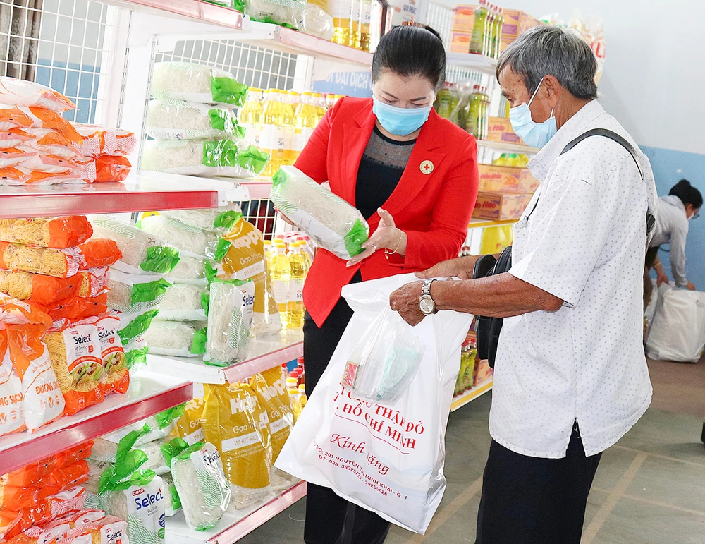 Tình nguyện viên giúp người khó khăn chọn nhu yếu phẩm tại phiên chợ nhân đạo tổ chức ở huyện Nhà Bè
