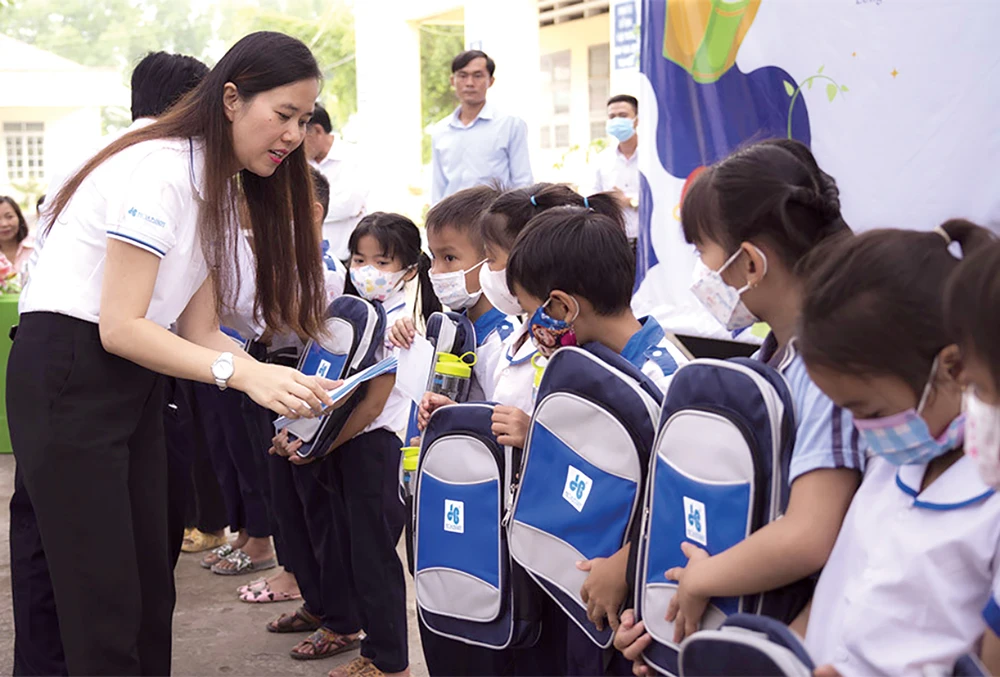Bà Trần Kim Ngân - Giám đốc truyền thông Tập đoàn Xây dựng Hòa Bình đang trao cặp cho các em học sinh