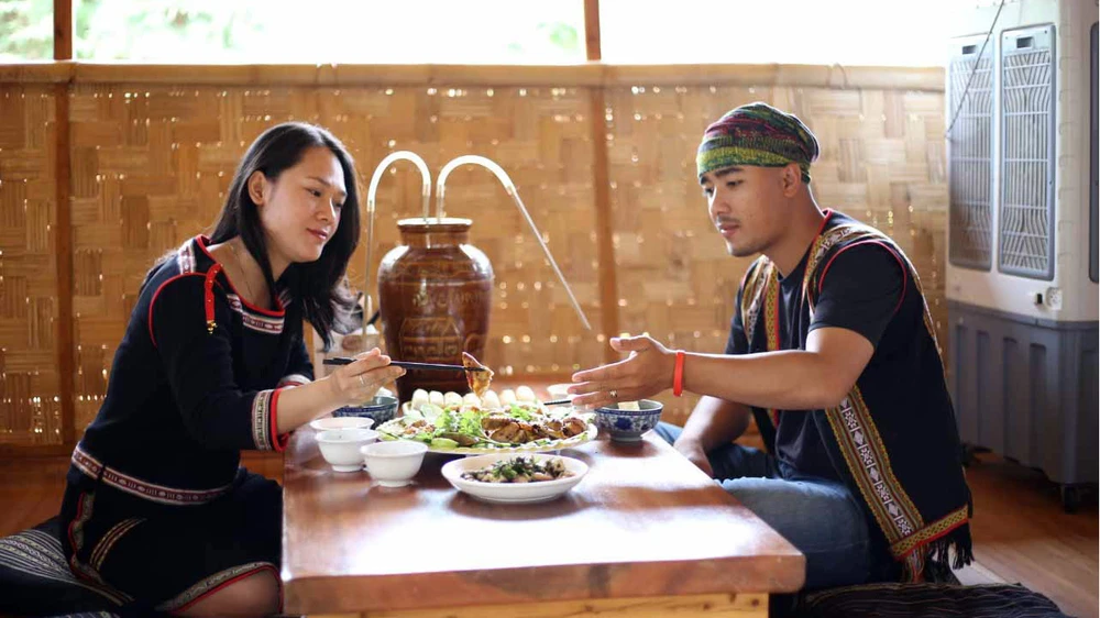 Du khách thích thú khi được mặc trang phục và thưởng thức ẩm thực của người M’Nông tại buôn Le, huyện Lắk