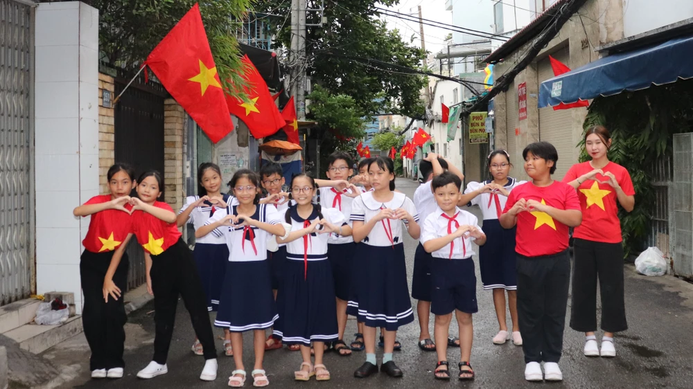 Các em thiếu nhi tạo dáng và bày tỏ niềm vui bên tuyến "Đường cờ Tổ quốc" đường Xóm Chiếu trong ngày ra mắt