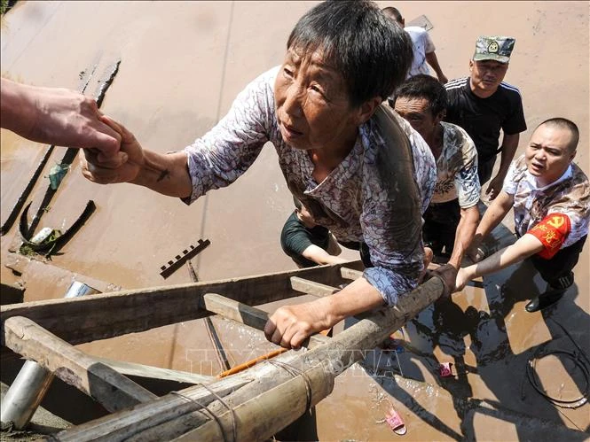 Nhân viên cứu hộ giúp sơ tán người dân khỏi các khu vực ngập lụt tại Dazhou, tỉnh Tứ Xuyên, Trung Quốc, ngày 12-7-2021. Ảnh: AFP/TTXVN