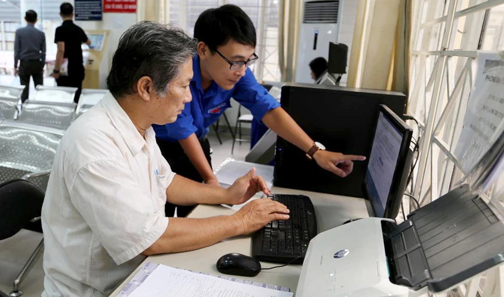 Công chức UBND quận Bình Thạnh hướng dẫn người dân thực hiện đăng ký hồ sơ qua mạng. Ảnh: Thái Phương