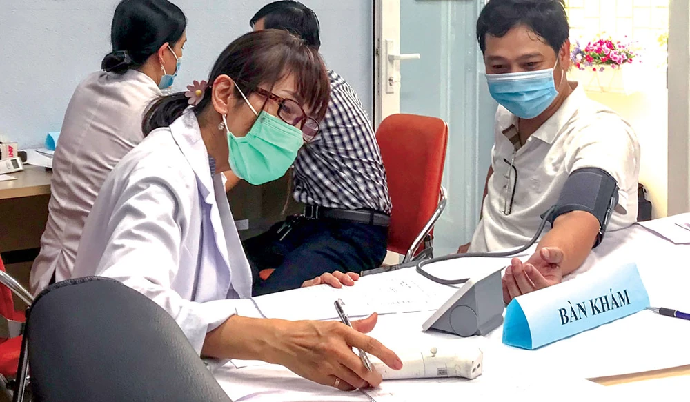 Nhân viên y tế đo huyết áp cho người dân trước khi tiêm vaccine phòng Covid-19