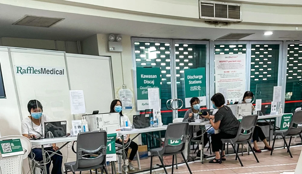 Một phụ nữ Singapore được tư vấn về những tác dụng phụ sau khi chích mũi vaccine thứ 3 trước khi lấy giấy chứng nhận, tại một trung tâm tiêm chủng cộng đồng do Tập đoàn Y tế Raffles Medical điều hành theo ủy nhiệm của chính phủ. 