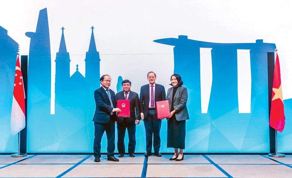 Bộ trưởng Bộ Kế hoạch - Đầu tư Nguyễn Chí Dũng (thứ hai từ trái sang) và Bộ trưởng Tan See Leng (phải sang) chứng kiến lễ ký Biên bản, nhân Hội nghị Bộ trưởng về Kết nối Kinh tế Việt Nam-Singapore lần thứ 16.