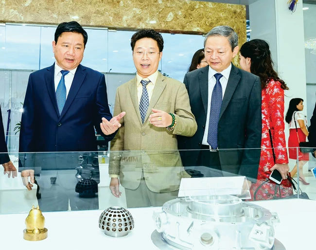 Bí thư Thành ủy TPHCM Đinh La Thăng (trái), Phó Chủ tịch UBND TPHCM Lê Văn Khoa (phải) và ông Châu Bá Long trong một đợt tìm hiểu dây chuyền sản xuất của Công ty Minh Nguyên - một trong số ít công ty Việt Nam tham gia cung ứng sản phẩm phụ trợ cho Samsung