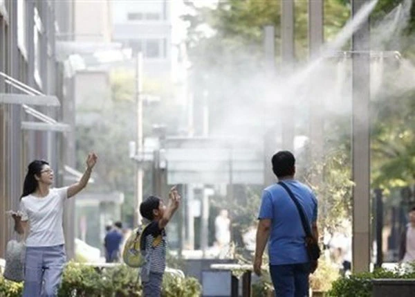 Người dân giải nhiệt tại các vòi phun nước ở Tokyo. (Nguồn: Kyodo/TTXVN)