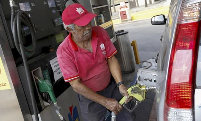 Một công nhân đang bơm nhiên liệu cho xe tại một trạm xăng ở Caracas, Venezuela. Ảnh: Marco Bello/Reuters