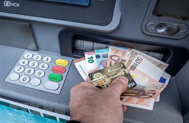 Khách hàng rút tiền đồng euro tại một máy rút tiền tự động ở Pháp. (Nguồn: AFP/TTXVN)