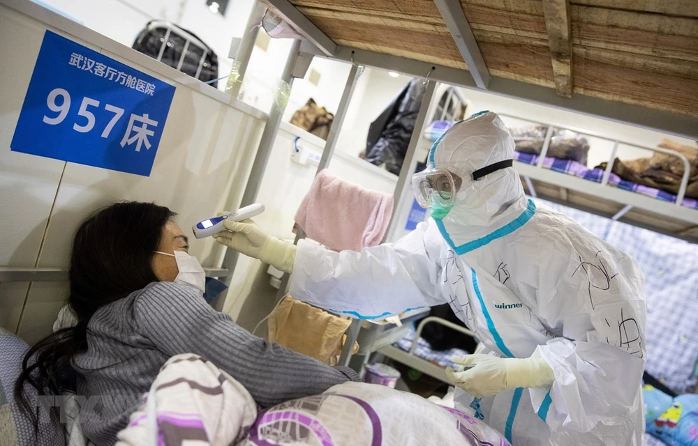 Nhân viên y tế kiểm tra thân nhiệt một bệnh nhân nghi nhiễm COVID-19. (Ảnh: AFP/TTXVN)