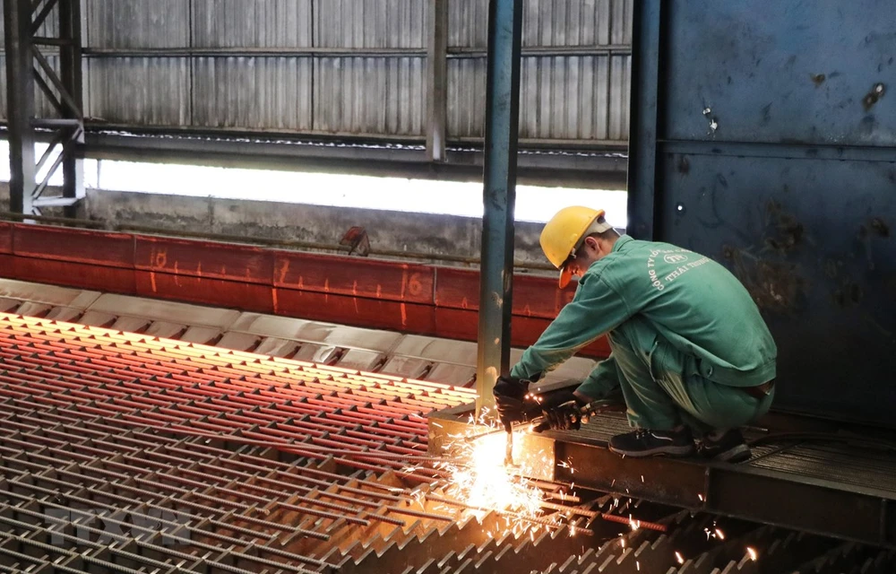 Công nhân Nhà máy cán thép Thái Trung (Công ty Cổ phần gang thép Thái Nguyên) lấy mẫu thép mới cán. (Ảnh: Hoàng Nguyên/TTXVN)