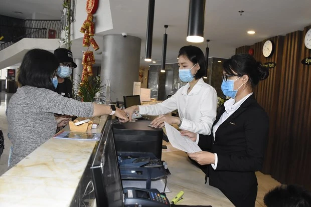 Nhân viên lễ tân khách sạn CAO Vũng Tàu đang tiến hành đo thân nhiệt cho du khách khi nhận phòng tại quầy lễ tân của khách sạn. (Ảnh: Ngọc Sơn/TTXVN)