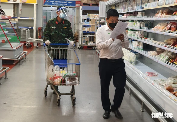 Cán bộ phường cùng bộ đội đi chợ giúp người dân ở siêu thị tại TP Thủ Đức - Ảnh: MINH HÒA