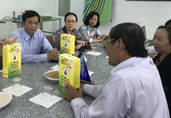 Ông Hồ Quang Cua (phải) giới thiệu gạo thơm ST25 hữu cơ trồng trên đất nuôi tôm - Ảnh: KHẮC TÂM