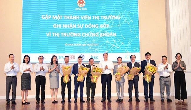 Thứ trưởng Nguyễn Đức Chi (thứ 6 từ trái sang) tặng hoa cảm ơn các thành viên thị trường ngày 28-7.