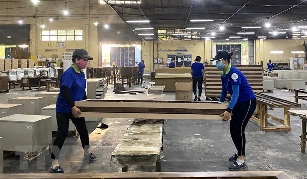 Công nhân Công ty Cổ phần Chế biến gỗ Thuận An kiểm tra các chi tiết khung giường gỗ. (Ảnh: Hồng Nhung/TTXVN)